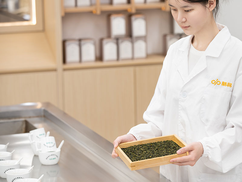 Tea specialist evaluating green tea leaves for custom blending and product development
